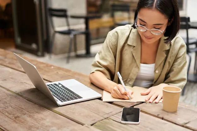 portrait-concentrated-girl-doing-homework-attending-online-course-making-notes-while-working